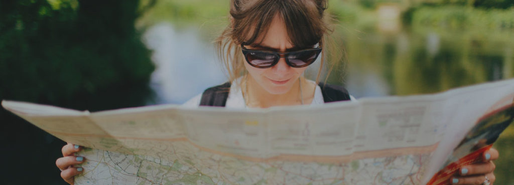 A person reading a map next to a river