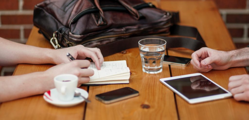 two people writing notes and talking in a coffee shop