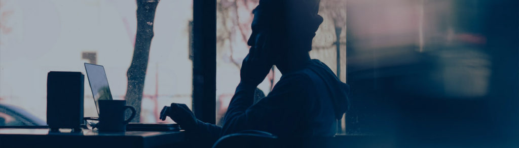 Silhouette of a person at their laptop.