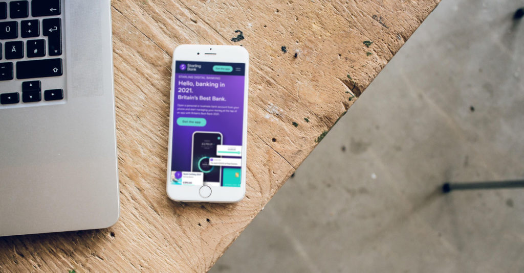 A laptop and smartphone on a table. The smartphone shows the website of an electronic-only bank