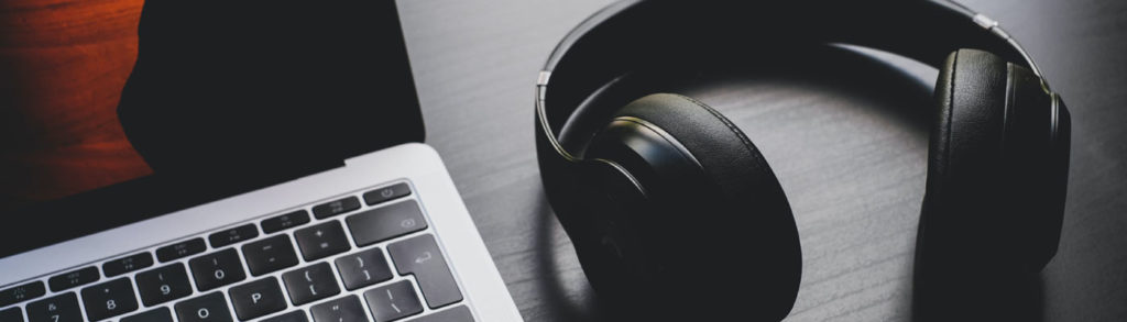 A picture of wireless headphones next to a laptop