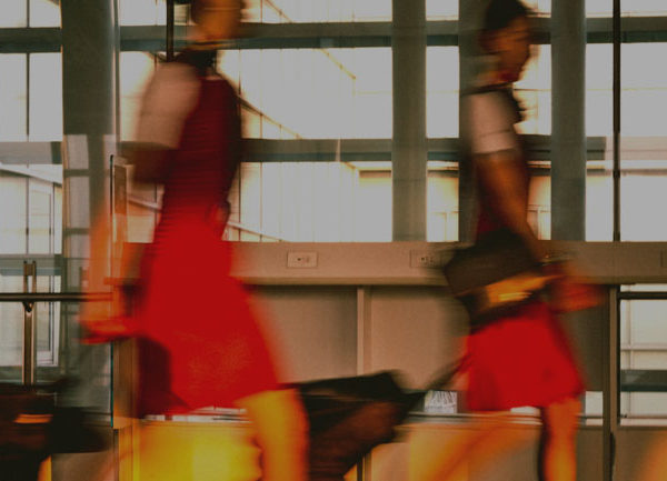 Image of two people pulling along suitcases in what could be an airport. The image is slightly blurred to give the impression of movement.