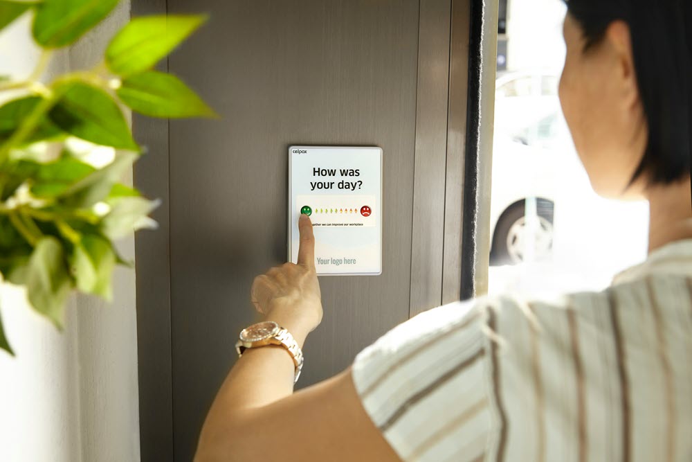 A woman interacting with a feedback interface, which asks, "How was your day?"