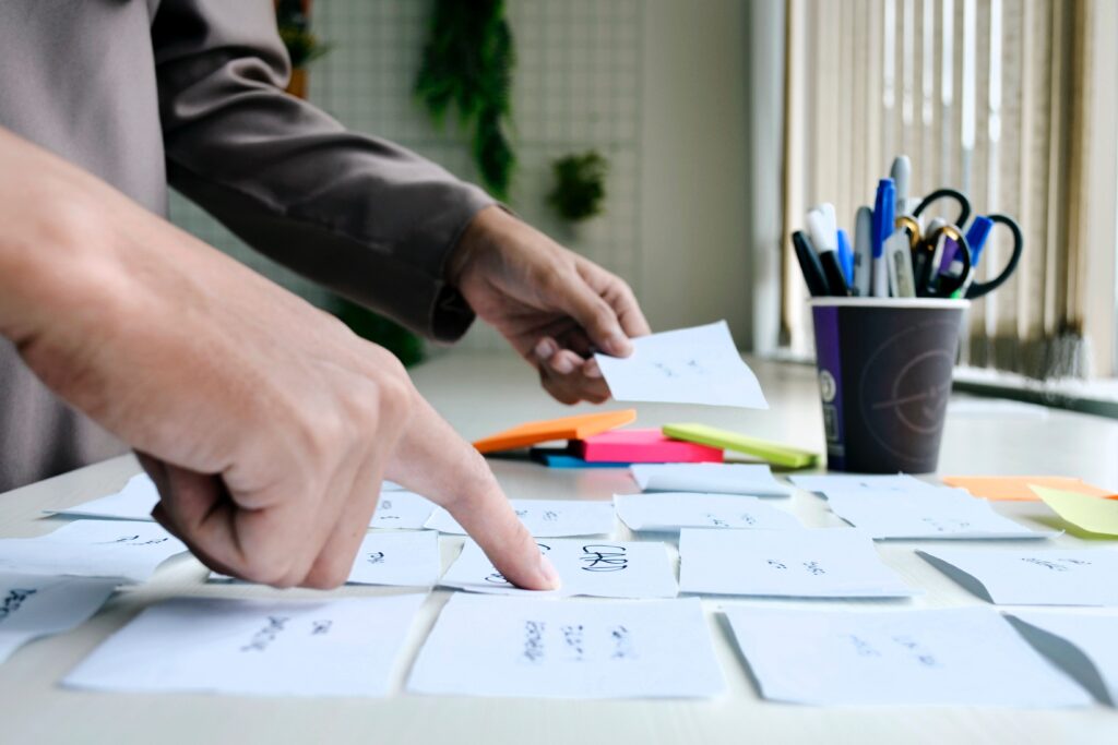 Finger pointing to notes listed on cards on a table