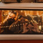 Three people looking out through a winow in, what looks like, an old VW Camper. The photo is zoomed in so we only see the rim around the window and three people looking out. by seljan-salimova-unsplash
